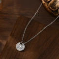 Detail of silver clover pendant necklace with micro-pave cubic zirconia on wood - Silver