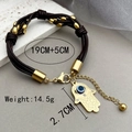 Lederwickelarmband mit goldenem Hamsa-Hand- und Evil Eye-Anhänger auf Marmor - Dunkelbraun/Gold