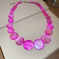 Detail of rose red shell disc necklace showing layered gradient beads and lobster clasp - Pink