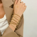 Set di bracciali a perline dorate multistrato indossato da una modella con blazer marrone - Set Multistrato di Perline di Riso Oro (DZ-151)