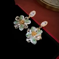 Makro-Detail luxuriöser Silberohrringe mit grünen Kristallblüten in einer Box - Grüne Strassblume (925 Silbernadel)