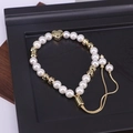 Detail of adjustable pearl bracelet with golden heart charm on a black display tray - Heart Pearl Beaded