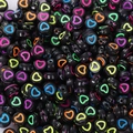 Close-up of bulk black acrylic beads featuring colorful heart patterns for DIY jewelry crafts - 4x7mm Black With Colored Hollow Heart (100pcs)