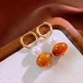 Macro shot of vintage gold hoop earrings with white pearl and amber resin bead charms - Coffee Geometric Style