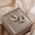 Macro detail of silver puffy hoop earrings with polished finish on a satin fabric - Oval Chunky Style / Steel