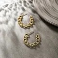 Detailed close-up of golden Cuban link C-shape earrings on a textured grey background - Cuban Link (073)