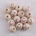 Macro shot of 20mm natural wood beads with smiley face patterns on a white cloth background - Lotus Wood Smile