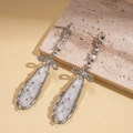 Orecchini a fiocco in argento con frange a goccia e zirconi su sfondo di pietra - Argento