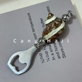 Vintage bottle opener featuring natural conch shell handle and silver metal accents - Striped Cat Eye Shell Bottle Opener