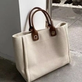 Makroaufnahme der Canvas-Tasche mit braunen Ledergriffen und seitlicher Falte - Gebrochenes Weiß