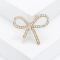Elegant gold-tone bow brooch with sparkling rhinestones on a white pedestal display - Gold