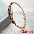 Detailed macro view of 14K gold filled wire wrapped bracelet with red garnet and pearls - Garnet