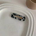 Detail shot of marble patterned acetate hair clip in a white ceramic plate - Black Marble Square
