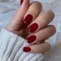 Short deep red solid color press-on nails displayed on hands over white fabric - Deep Red (JP2176)