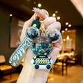 Detail of Mickey-shaped liquid keychain with glitter stars and Bubble silicone wristlet - Black Sitting Bear with Gradient Rope