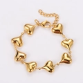 Detalle de pulsera dorada con dijes de corazón y cierre de langosta ajustable - Dorado