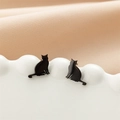 Close-up of minimalist black cat stud earrings hanging on a white ceramic plate - 750 Black