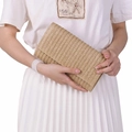 Beige straw woven clutch bag held by model for summer beach vacation style - Apricot