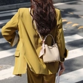 Close-up of beige lychee leather bucket bag with polka dot scarf and metal base feet - Milky Apricot