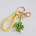 Detailed view of lucky four-leaf clover keychain with green rhinestones and yellow braided strap - Heart Strap / Green
