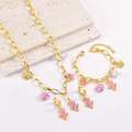 Gold jewelry set featuring pink tulip, butterfly and bee charms on a beige textured stone - Necklace + Bracelet + Earrings
