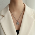 Collier à pendentif ovale à motif floral argenté sur un mannequin portant un blazer blanc cassé - P1024 Acier Argent Deux Fleurs Orchidées