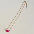 Detail of adjustable gold box chain with a pink glazed bean pendant on white surface - Universal Chain / Rose Red