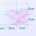 Pink glitter resin bow charm for jewelry making shown on a measurement grid board - Purple