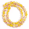Macro detail of Millefiori glass beads with yellow stripes and red flower patterns - Yellow Red Flower