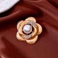 Detalle macro de un broche floral bañado en oro de 18k con perla y diamantes de imitación - Dorado