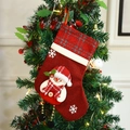 Red Christmas stocking with snowman doll and bells hanging on a festive Christmas tree - Snowman