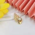 Detailed shot of a gold-tone shell charm with a white pearl on white silk fabric - Pearl Conch