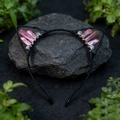 Detail of black cat ear headband with pink crystals on dark rock in nature setting - Peach Pink Cat Ears