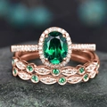 Macro shot of rose gold rings with oval emerald and diamonds on a textured stone surface - US 7 / Rose Gold