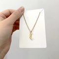 Detail of gold smiling moon pendant on fine chain necklace held against white card - DN110 Smiling Moon