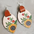 Makroaufnahme von Bohème-Tropfenohrringen mit Sonnenblumenmuster auf Holzmaterial - Sonnenblume und rote Blume mit braunem Leder (3)