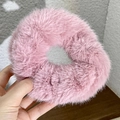 Close-up of a pink plush scrunchie held by hand showing soft fuzzy texture - Pink