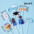 5-piece graduation cake topper set with cap and book designs in blue and orange theme - Youth Never Ends