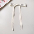 Detailed view of the white satin ribbon bow hair clip with elegant long streamers - Off White