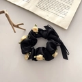 Chouchou en satin noir avec roses en tissu et longs rubans sur fond de livre ancien - Chouchou Camélia Noir