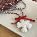 Detailed close-up of white wool felt snowflake pendant with red velvet bow on a woven cord - Snowflake Style