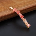 Detail shot of a golden hair clip featuring polished natural pink crystal gravel stones - Watermelon Quartz Gold