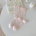 Light pink crew socks with ruffled edges and rib knit texture on a white table - One Size / Pink
