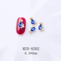 Detailed view of blue teardrop alloy nail charm with gold border on red nail art - Gold Base Blue Water Drop (8202)