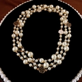 Detail van meerlagige camelia barok parelketting met zwart geëmailleerde hanger detail - Ketting - Goud