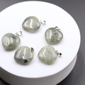 Natural labradorite heart pendants with grey-green tones and blue sheen on white stand - Labradorite