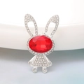 Macro shot of silver bunny charm with white rhinestones and a red gemstone center - Red