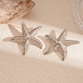 Close-up of starfish earrings with textured silver finish on a natural textured surface - 925 Sterling Silver Earring Post - Silver Textured Starfish Stud Earrings
