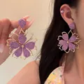 Dettaglio di grandi orecchini a fiore intrecciato viola con eleganti cornici dorate - Fiore a Cinque Petali Viola (Perno in Argento)