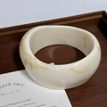 Wide ivory resin bangle with light brown marble texture on a rustic wood tray - White Yellow Swirl
